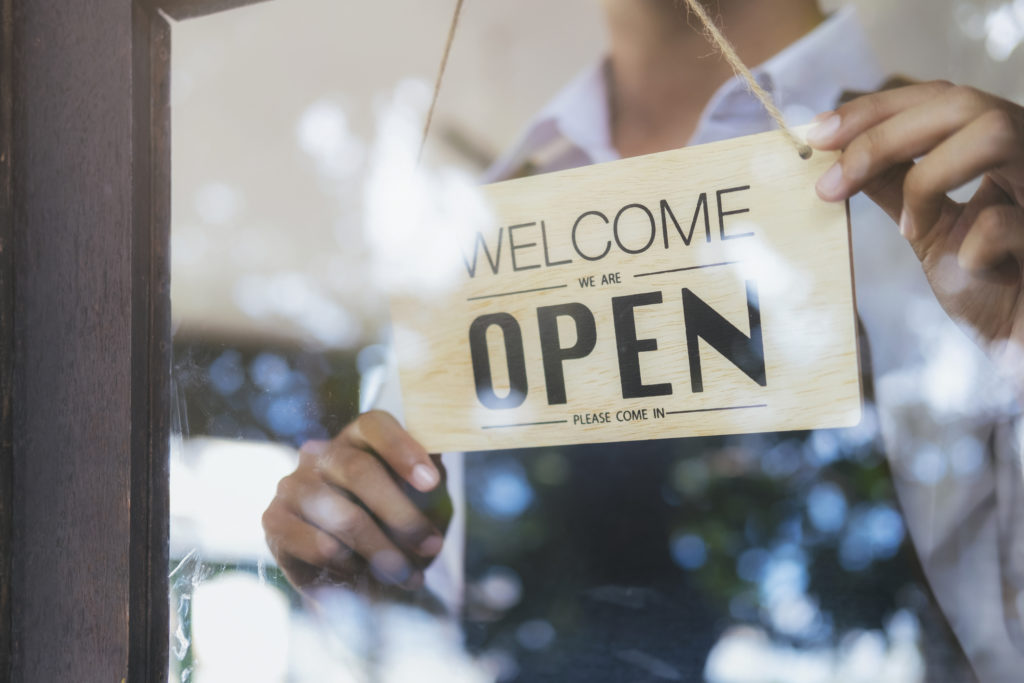 'Open' sign being turned on the door of a cafe